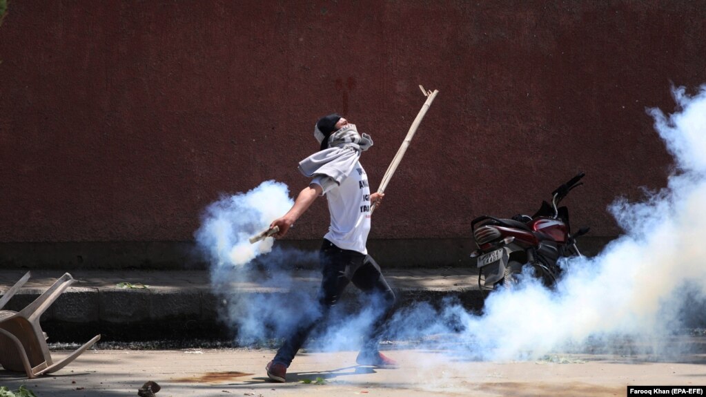 FILE: A Kashmiri student throws back a tear smoke shell at Indian police personnel during clashes in Srinagar, the summer capital of Indian Kashmir on May 14.