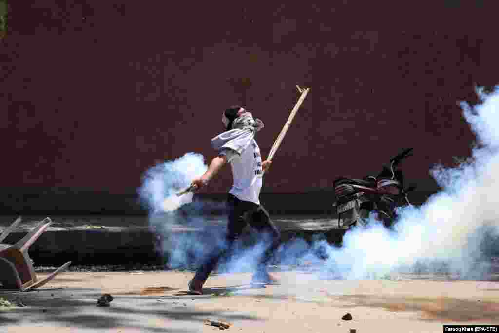 A Kashmiri student throws back a tear-gas shell at Indian police during clashes in Srinagar, the summer capital of Indian Kashmir. Protests erupted against the alleged rape of a 3-year-old girl by a local boy. The protesters were demanding extreme punishment for the accused, who has been arrested by police. (epa-EFE/Farooq Khan)