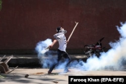 Кашмирский юноша бросает обратно в индийских полицейских гранату со слезоточивым газом. Город Сринагар, май 2019 года
