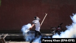 A Kashmiri student throws back a tear smoke shell at Indian police on May 14.