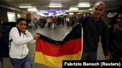 Migrantët e mbajnë flamurin gjerman pasi arritën me tren nga Austria në një stacion hekurudhor afër Berlinit