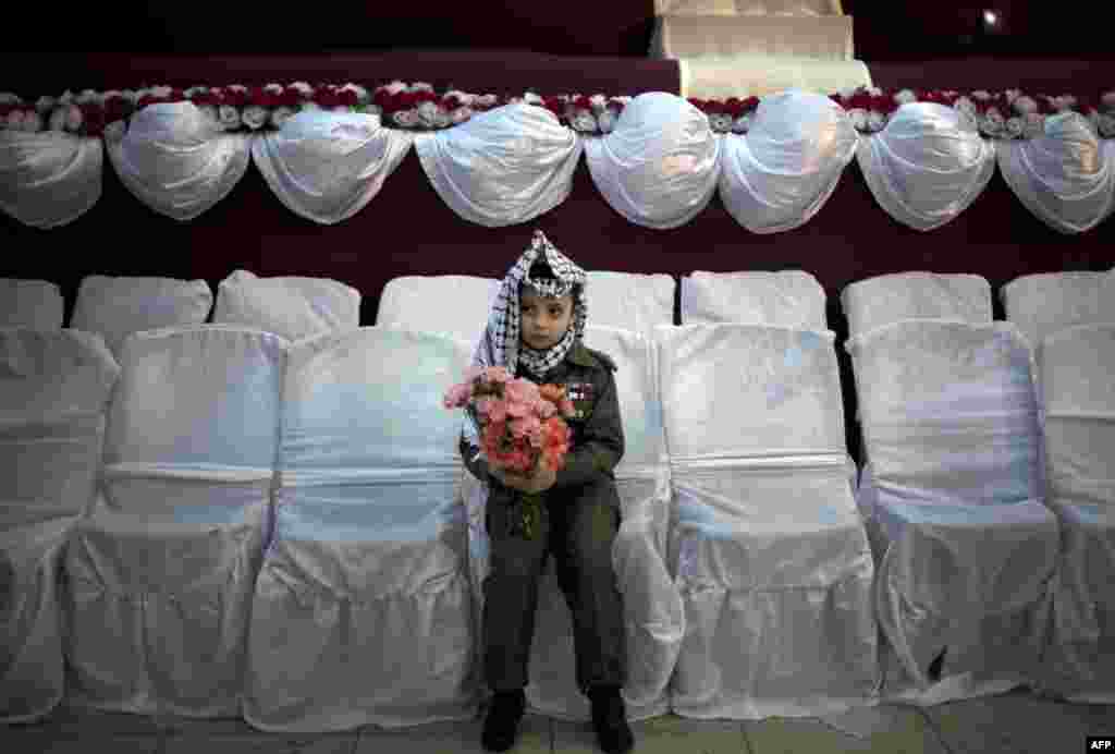 A young Palestinian wearing a traditional Keffiyeh head scarf carries a bouquet of flowers ahead of a mass wedding ceremony in Gaza City. (AFPMahmud Hams)