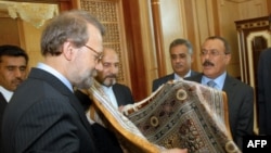 Iranian Parliament Speaker Ali Larijani (L) offers Yemeni President Ali Abdullah Saleh (R) a Persian carpet during their meeting in Sanaa on May 14, 2009. Larijani is on an official visit to neighbouring Yemen. AFP PHOTO/KHALED FAZAA / AFP PHOTO / KHALED