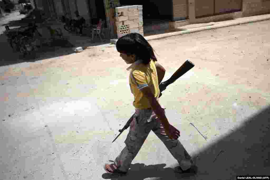 A young Syrian boy holds an old rifle as he helps fighters belonging to the rebel battalion in the southern town of Maaret al-Numan in Idlib Province on June 13. (AFP/Daniel Leal-Olivas)