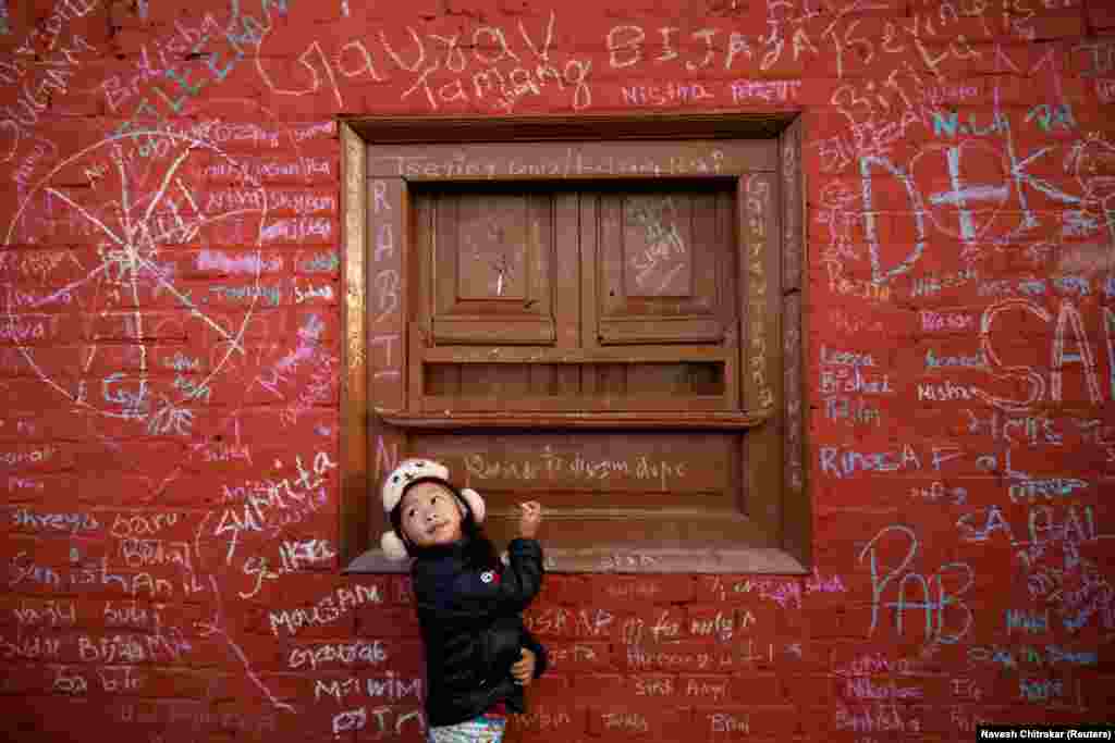 A Nepalese girl looks toward her father as she writes on the wall of a Saraswati temple during the Shreepanchami festival in Kathmandu on February 11. (Reuters/Navesh Chitrakar)