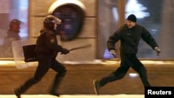 Міліцыянт гоніцца за ўдзельнікаў пратэсту апазыцыі супраць вынікаў прэзыдэнцкіх выбараў, 19 сьнежня 2010 года