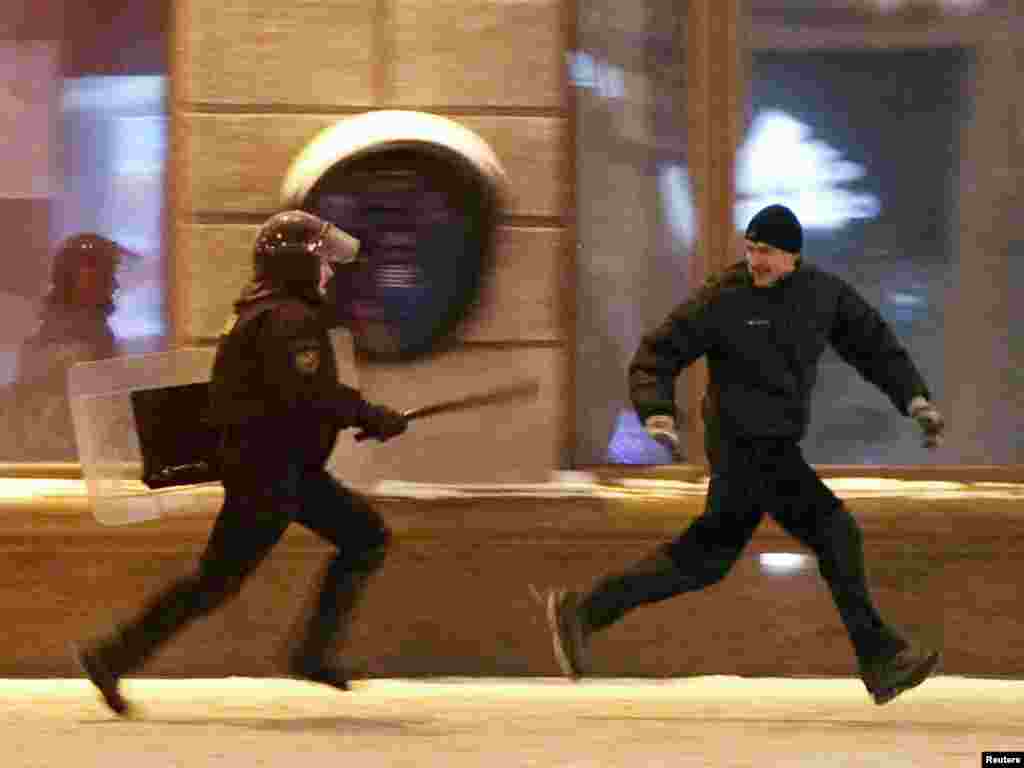 Riot police chase an opposition protester.