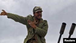 A rebel fighter reacts to incoming shells fired by soldiers loyal to Moammar Qaddafi. The rebels started out strong, but appear to be losing territory day-by-day.