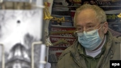 France -- A man working in a news-stand wears a protective face mask in central Paris, France, 04May2009