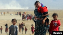 Displaced people from the minority Yazidi sect, flee violence from Islamic State (IS) militants in the town of Sinjar in northern Iraq in August 2014.