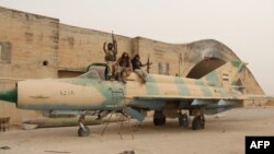 Members of Al-Qaeda's Syrian affiliate and its allies sit on top of a former Syrian Army jet after seizing the Abu Duhur military airport, the last regime-held military base in northwestern Idlib Province on September 9.