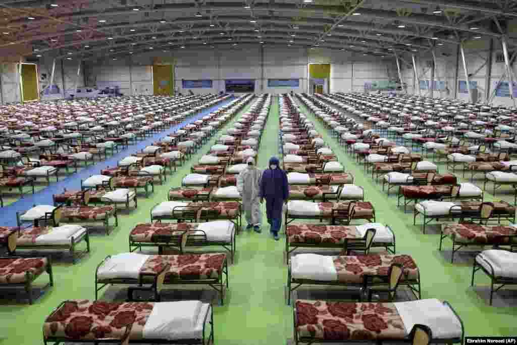 IRAN -- People in protective clothing walk past rows of beds at a temporary 2,000-bed hospital for COVID-19 coronavirus patients set up by the Iranian army at the international exhibition center in northern Tehran, March 26, 2020