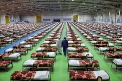 People in protective clothing walk past rows of beds at a temporary 2,000-bed hospital for COVID-19 patients set up by the Iranian Army at an exhibition center in northern Tehran on March 26.