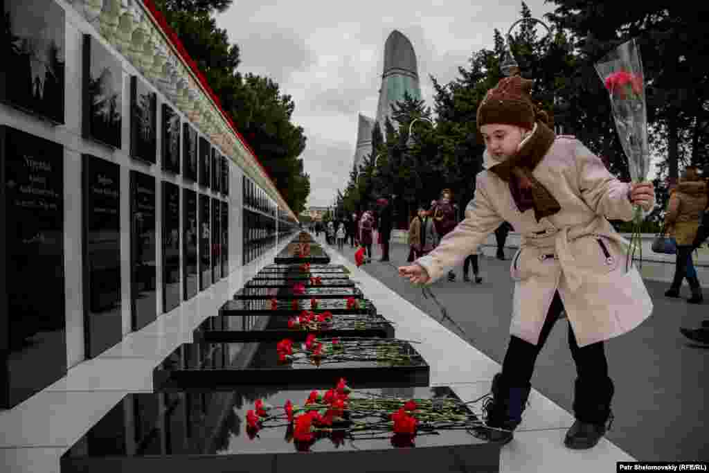 A girl lays flowers at the Alley of Martyrs memorial