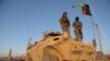 Afghan security personnel stand guard on an armored vehicle at a checkpoint in Ghazni on October 13.