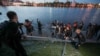 Протестующие в Екатеринбурге выбрасывают часть ограждения вокруг предлагаемого властями места стройки храма в реку Исеть.