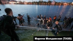 Протестующие в Екатеринбурге выбрасывают часть ограждения вокруг предлагаемого властями места стройки храма в реку Исеть.