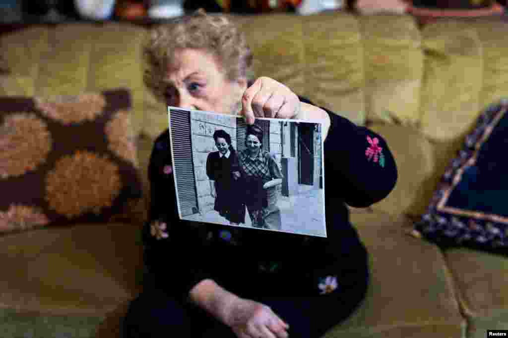 Jona Laks shows a photo of her and her older sister Chana, during an interview in her house in Tel Aviv, Israel January 21, 2020. Before her trip to Poland Jona Laks had recounted her arrival at Auschwitz. With her sisters and thousands of other Jews from the Lodz ghetto, she was transported by train. In cattle carts without windows, she thinks the journey lasted about three days. Being a twin helped her to survive, but it was also a reason for her to be subjected to pseudo-medical experiments.