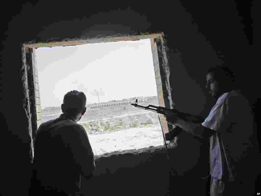 Rebel combatants observe the fighting near Muammar Qaddafi's main compound in the Bab al-Aziziya district of Tripoli. 