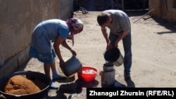 Жанар и ее муж Алибек остужают только что сваренное просо холодной водой. Шалкар, 4 мая 2013 года.