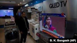 A Pakistani shopkeeper listens to Malala Yousafzai addressing a reception in Islamabad on March 29.
