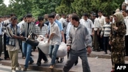Local residents carry the body of a victim of the clashes between government forces and local protesters at the central square in the Uzbek town of Andijon on May 14, 2005.