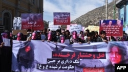 Members of the Afghan Solidarity Party wearing masks of the bloodied face of the woman who was lynched by a mob chant slogans during a protest against the attack in Kabul on March 23.