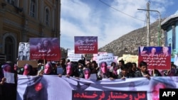 Members of the Afghan Solidarity Party wearing masks of the bloodied face of the woman who was lynched by a mob chant slogans during a protest against the attack in Kabul on March 23.
