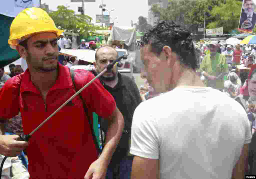 A supporter of ousted Egyptian President Muhammad Morsi is doused with water on a hot day during a protest in Cairo on July 12. 