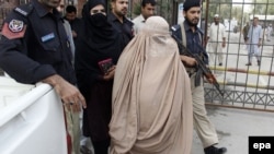 Pakistani security officials escort Afghan refugee woman Sharbat Gula (C, in burqa), after a medical examination at a hospital before she was presented to a court in Peshawar on November 4.