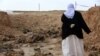 A Yazidi woman searches for clues in February 2015 as to the whereabouts of missing relatives among remains at a mass grave of victims of Islamic State (IS) militants in Iraq's Sinjar region.