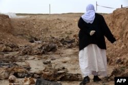 Пожилая езидка ищет останки своих родственников, убитых исламистами, в обнаруженной на севере Ирака общей могиле. Февраль 2015 года