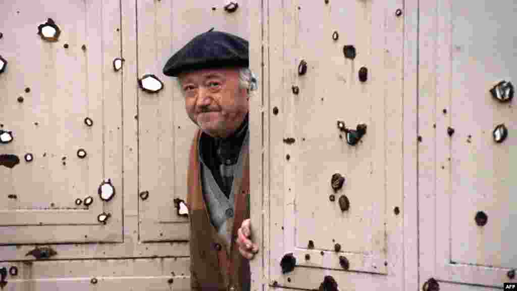 A resident looks out from the bullet ridden door to this house, November 29, 1991.