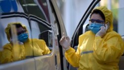 Armenia -- A doctor wearing a face mask and protective gear gives a call as she stands next to an ambulance at the Grigor Lusavorich Medical Centre in Yerevan, June 1, 2020