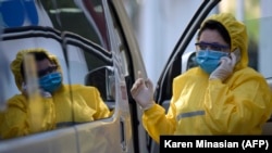 Armenia -- A doctor wearing a face mask and protective gear gives a call as she stands next to an ambulance at the Grigor Lusavorich Medical Center in Yerevan, June 1, 2020
