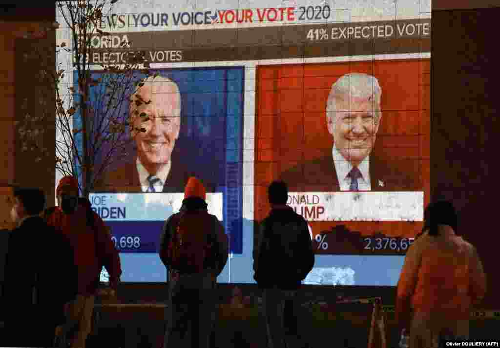 People watch a big screen displaying the live election results in Florida at Black Lives Matter plaza across from the White House on election night in Washington, DC on November 3, 2020.