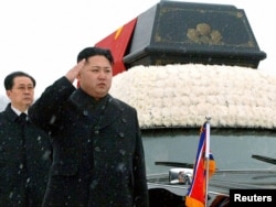 Новый лидер Северной Кореи Ким Чен Ын стоит рядом с машиной, на которой установлен саркофаг с телом Ким Чен Ира. Пхеньян, 28 декабря 2011 года.