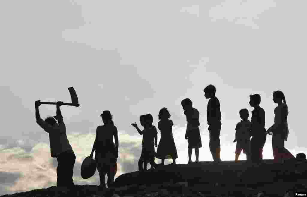 Children stand next to a laborer working on the banks of Ganges River in the northern Indian city of Allahabad. (Reuters/Jitendra Prakash)