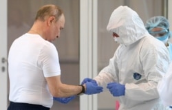 Russian President Vladimir Putin is helped before donning a protective suit as he visited a hospital for patients infected with the coronavirus on the outskirts of Moscow on March 24.