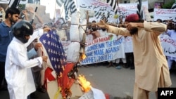 Пакистандык суннилер анти-исламчыл фильмге каршы өткөн демонстрация учурунда АКШнын желегин өрттөшүүдө. Карачи шаары. 16-сентябрь, 2012