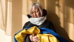Татьяна Борисенко держит в руках украинский флаг, который ей удалось тайно прятать от сепаратистов на протяжении всего плена. На нем – подписи 12 человек, вместе с которыми она оказалась в заключении. Борисенко была медиком-волонтером добровольческого батальона "Айдар" и оказалась в плену в сентябре 2015 года
