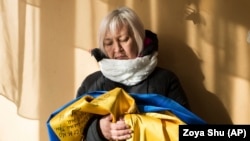 Татьяна Борисенко держит в руках украинский флаг, который ей удалось тайно прятать от сепаратистов на протяжении всего плена. На нем – подписи 12 человек, вместе с которыми она оказалась в заключении. Борисенко была медиком-волонтером добровольческого батальона "Айдар" и оказалась в плену в сентябре 2015 года