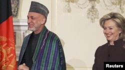 U.S. Secretary of State Hillary Clinton (right) walks with Afghan President Hamid Karzai before the expanded bilateral meeting at the State Department in Washington on May 11.