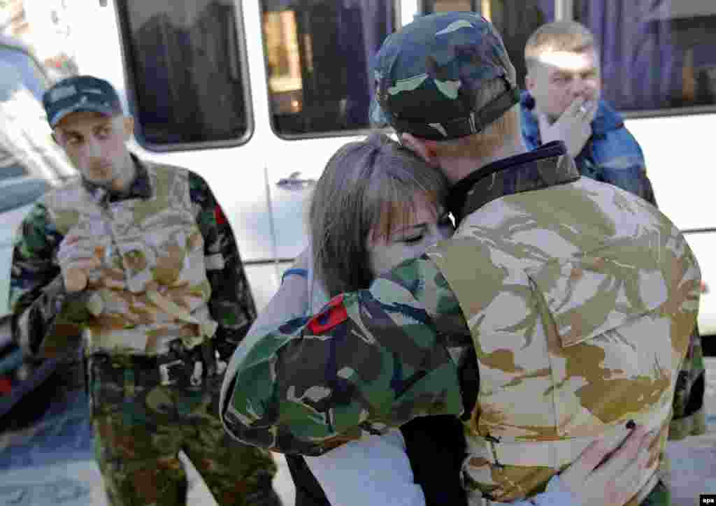 A young Ukrainian volunteer and member of the Maidan self defense forces is embraced by his girlfriend on Kyiv's Independence Square before his deployment at a training facility.
