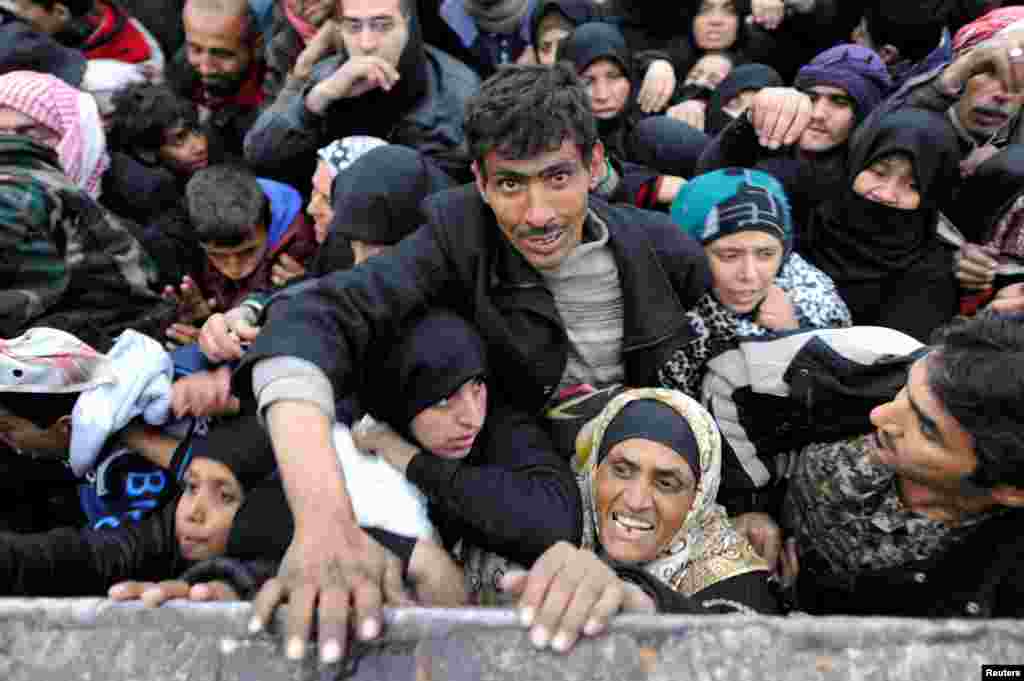 Hələbdən köçürülən suriyalılar hökümət qüvvələrinin nəzarətində olan Jibrində yemək növbəsində. (Reuters/Omar Sanadiki)