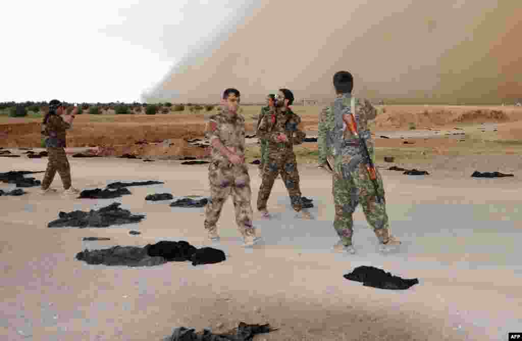 Fighters from the Syrian Democratic Forces (SDF) walk along a road dotted with dozens of black veils shed by women after they crossed into SDF territory near Tishreen Farms on the northern outskirts of Raqqa, Syria, on May 2. (AFP/Ayham al-Mohammad)