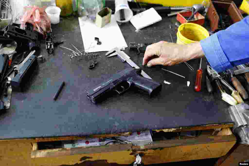 A weapons designer picks up a prototype of a handgun in the manufacturing hall of Zastava Arms.