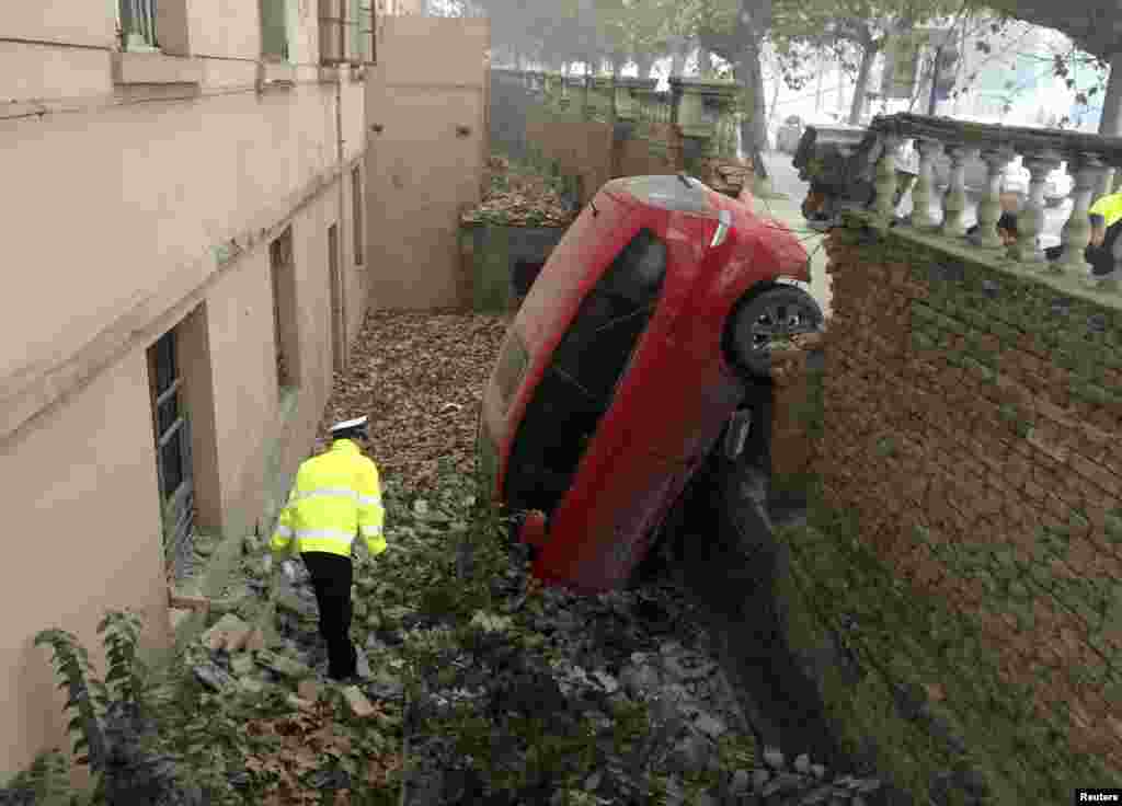 A policeman looks at a car that fell into a pit after crashing through a brick wall on a hazy day in Xianyang, Shaanxi Province, China. Local police said the accident occurred when the driver could not see the road clearly due to thick fog. No one was injured. (Reuters)