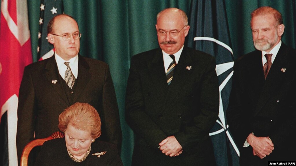 Ministrul ceh de externe Jan Kavan (stânga), ministrul ungar de externe Janos Martonyi (c) şi ministrul polonez de externe Bronislaw Geremek (dreapta) urmărind cum secretarul de stat american Madeleine Albright semnează documentul de aderare a celor trei ţări la NATO