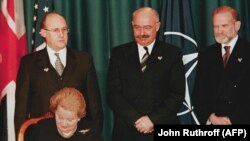 Ministrul ceh de externe Jan Kavan (stânga), ministrul ungar de externe Janos Martonyi (c) şi ministrul polonez de externe Bronislaw Geremek (dreapta) urmărind cum secretarul de stat american Madeleine Albright semnează documentul de aderare a celor trei ţări la NATO